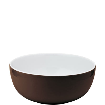 Ein geschwungener, runder Schüssel in Braun mit einem glänzenden, weißen Innenleben. Die Schüssel hat eine glatte Oberfläche und ist ohne Dekoration. Der Hintergrund ist neutral und hell. Ideal für Salate oder Snacks.