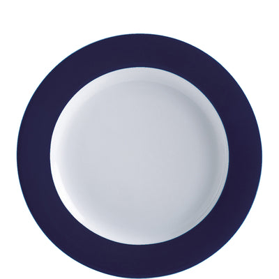 Ein runder Teller mit einem weißen Innenbereich und einem breiten, dunkelblauen Rand. Der Teller hat eine schlichte, elegante Form und eignet sich für den Alltag sowie besondere Anlässe. Der starke Kontrast zwischen dem weißen Zentrum und dem dunkelblauen Rand betont die visuelle Attraktivität des Geschirrs. Der Teller wirkt modern und stilvoll und kann für vielseitige Serviermöglichkeiten verwendet werden.