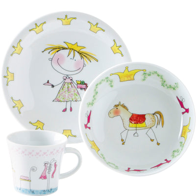 Ein Set aus buntem Kindergeschirr bestehend aus einem tiefen Teller, einem flachen Teller und einer Tasse. Der flache Teller zeigt ein lächelndes Mädchen mit einer Krone und einer Torte, umgeben von goldenen Kronen. Der tiefe Teller zeigt ein Pferd mit einer roten Decke, verziert mit grünen Ranken und lila Elementen. Die Tasse ist in sanften Farben gehalten und zeigt drei stilisierte Figuren in verschiedene Kleider. Das Geschirr hat eine spielerische und fröhliche Gestaltung, ideal für Kinder.