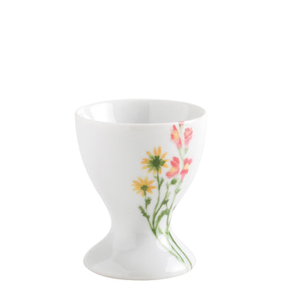 Weißes Eierbecher mit einer eleganten, blühenden Pflanzenmotiv-Dekoration in sanften Farbtönen. Die Form ist asymmetrisch mit einem breiten, runden Fuß und einer schmalen Öffnung oben. Das Geschirr strahlt eine frische, fröhliche Ästhetik aus und eignet sich ideal für den Tischgedeck während des Frühstücks.