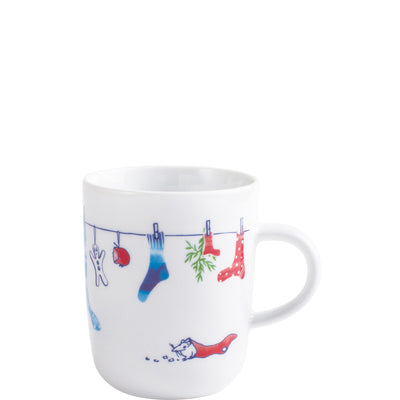 Eine weiße Tasse mit einem fröhlichen Design, das Kleidungsstücke wie Socken und Handschuhe zeigt, die an einer Wäscheleine hängen. Die Socken sind in verschiedenen Farben, darunter blau und rot mit Punkten. Unter der Leine ist ein kleiner Cartoon-Kater abgebildet, der mit einem grünen Blatt spielt. Die Tasse hat eine runde Form und einen klaren Henkel. Das Gesamtdesign vermittelt eine gemütliche, verspielte Stimmung.
