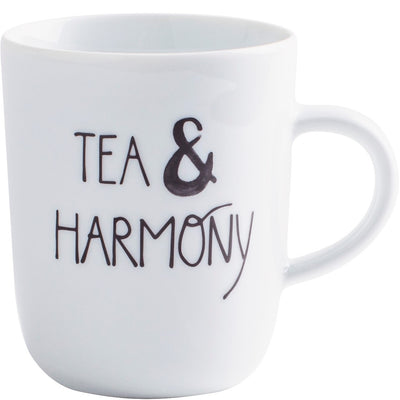 Eine weiße Tasse mit schwarzer Schrift, auf der die Worte „TEA & HARMONY“ geschrieben stehen. Die Tasse hat eine schlichte, modern geformte Optik und einen Henkel auf der rechten Seite. Sie ist leer und vor einem neutralen Hintergrund positioniert.