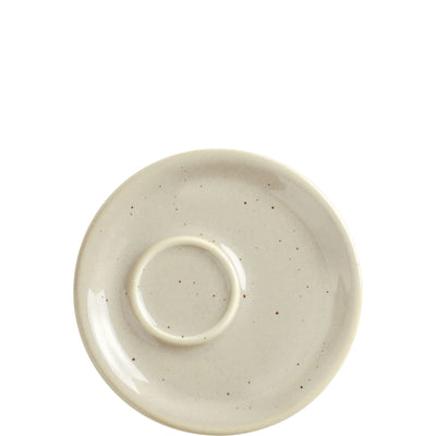 Eine obere Ansicht eines runden, cremefarbenen Untertellers mit leicht rauer Oberfläche und kleinen, braunen Sprenkeln. In der Mitte befindet sich ein erhöhter Ring, der wahrscheinlich zur Ablage einer Tasse dient. Der Teller vermittelt einen minimalistischen und modernen Look.
