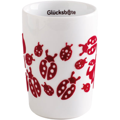 Ein weißer Becher mit buntem Design, der mit roten Marienkäfern verziert ist. Die Marienkäfer besitzen schwarze Punkte auf ihrem Schildchen. Am oberen Rand des Bechers steht der Schriftzug „Glücksboten“. Der Becher hat eine gerade Form und eine glatte Oberfläche.