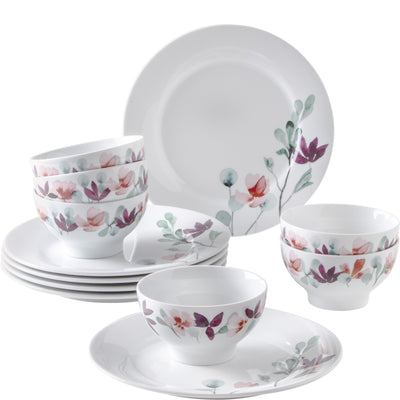 Ein set von Keramiktellern und Schalen mit einem floralen Design in sanften Farben. Im Vordergrund befinden sich zwei weiße Schalen, während im Hintergrund mehrere Schalen und Teller gestapelt sind. Die Oberflächen sind mit stilisierten Blumen und Blättern verziert, die in zarten Rosa- und Grüntönen gehalten sind.