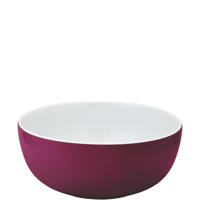 Eine runde Schüssel mit hohem Rand, außen in einem kräftigen Magenta-Ton und innen in schlichtem Weiß. Die Schüssel hat eine glatte Oberfläche und eignet sich ideal für Servieren von Speisen oder Salaten. Der Hintergrund ist einfarbig und hebt die Schüssel hervor.