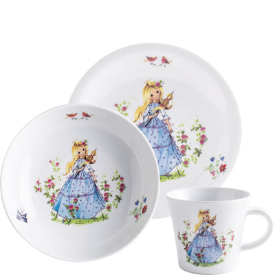 Drei Geschirrteile: ein flacher Teller, eine Schüssel und eine Tasse. Alle Teile sind weiß und schmücken Illustrationen eines Mädchens mit langen, blonden Haaren in einem blauen Kleid, umgeben von Blumen und Vögeln. Der Teller ist groß und flach, während die Schüssel rund und die Tasse klein und zylindrisch ist. Die farbenfrohen Designs verleihen dem Geschirr einen kindlichen, verspielten Charakter.