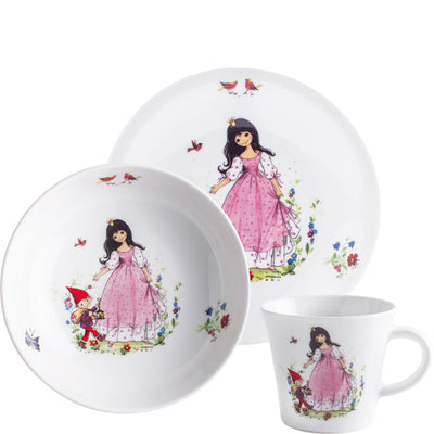 Drei Geschirrteile mit verspielten Kindermotiven. Ein tiefes Teller, eine flache Platte und eine Tasse zeigen eine märchenhafte Szene mit einem Mädchen in einem pinken Kleid, das einen kleinen gnomartigen Charakter umgibt. Umgeben von bunten Blumen, Schmetterlingen und Vögeln, strahlen die Teile eine kindliche, fröhliche Atmosphäre aus. Das Geschirr hat einen weißen Hintergrund und bunte, detaillierte Illustrationen.