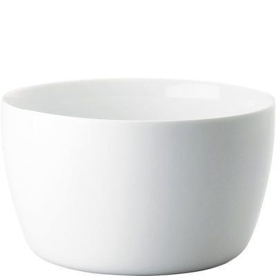 Ein freistehender, runder weißer Keramikbecher oder eine Schüssel mit glatter Oberfläche und leicht abgerundetem Rand. Die Schüssel hat keine Verzierungen und vermittelt einen modernen, minimalistischen Stil. Sie steht auf einer neutralen Oberfläche und ist gut belichtet, wodurch ihre Form und Farbe klar zur Geltung kommen.