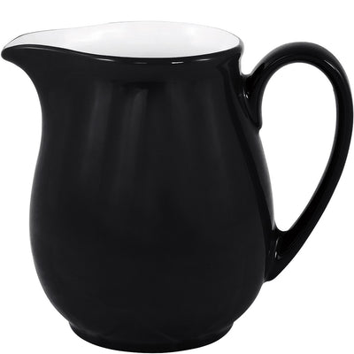 Ein schwarzer Kännchen aus Keramik mit einer glänzenden Oberfläche. Der obere Rand ist innen weiß und hat eine geschwungene Lippe zum Ausgießen. Der Korpus ist rundlich und verjüngt sich nach unten. Der Henkel ist seitlich angebracht und hat eine geschwungene Form, die einen komfortablen Halt ermöglicht. Das Kännchen steht auf einer neutralen Unterlage und hebt sich deutlich vom Hintergrund ab.